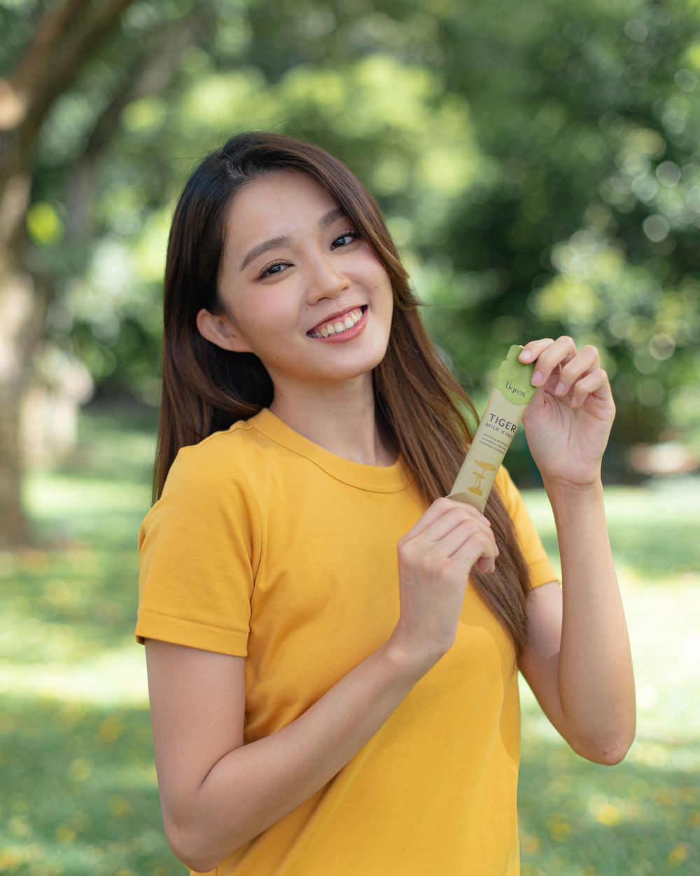 A woman holding a Tiger Milk King sachet outdoors
